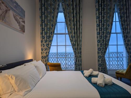 a bedroom with a large bed with two windows at Acqua Beach Weymouth in Weymouth