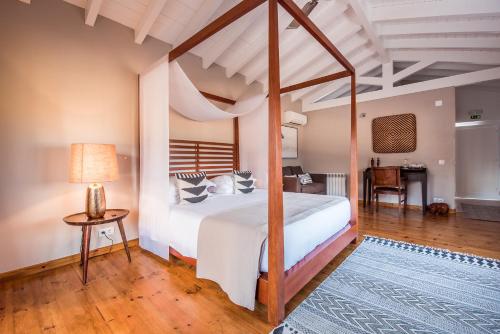 a bedroom with a large bed and a table at Paraiso Escondido in São Teotónio