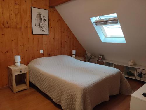 1 dormitorio con cama blanca y tragaluz en Appartement Duplex dans Résidence VAL DE ROLAND en Luz-Saint-Sauveur