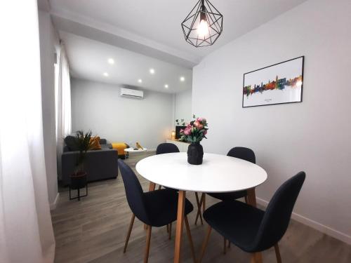 uma sala de jantar com uma mesa branca e cadeiras em Victoria Flat F&M Moderno, acogedor y céntrico em Málaga