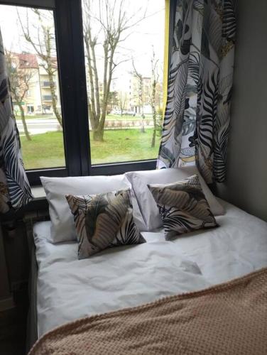 a bed with pillows in front of a window at Przytulne mieszkanko in Oświęcim