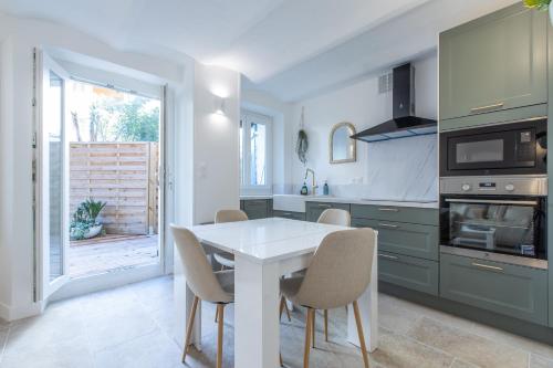 - une cuisine avec une table et des chaises blanches dans l'établissement LB Vacation Rentals I A Quiet Place with Garden in the Heart of Cannes, à Cannes