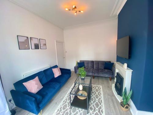 a living room with a blue couch and a fireplace at Manchester House in Blackpool