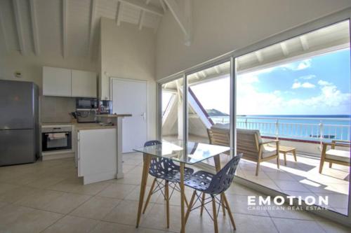 a kitchen with a table and chairs and a view of the ocean at Deux pièces sur la belle plage de Grand Case in Grand Case