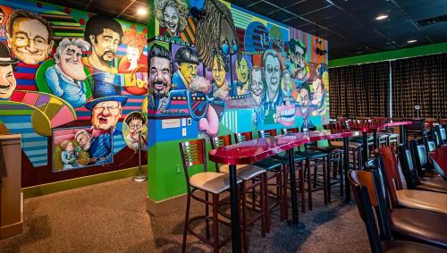 a restaurant with tables and chairs and a mural at Magnuson Grand Harrisburg in New Cumberland
