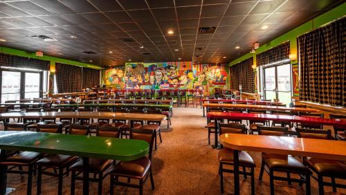 a dining room with tables and chairs and a mural at Magnuson Grand Harrisburg in New Cumberland