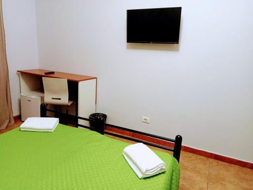 Habitación con cama verde, escritorio y TV. en Termini luxury home en Roma