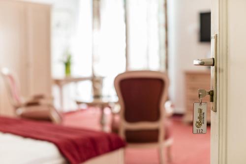 a room with a bed and a door with a chair at Grand Hotel Bellevue - adults only in Merano