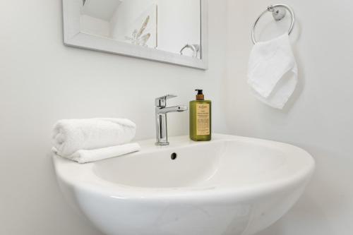a white bathroom sink with a bottle of soap on it at U2 - Beachy Paradise -Private & Spacious 2bdrm apt in Hamilton