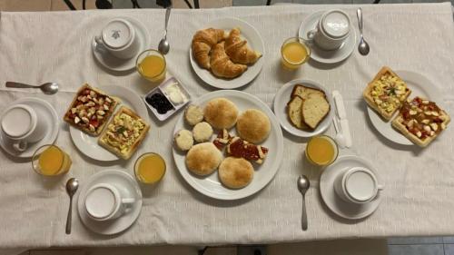 a table with plates of breakfast foods and orange juice at Hostal Alto Ayre Salta in Salta