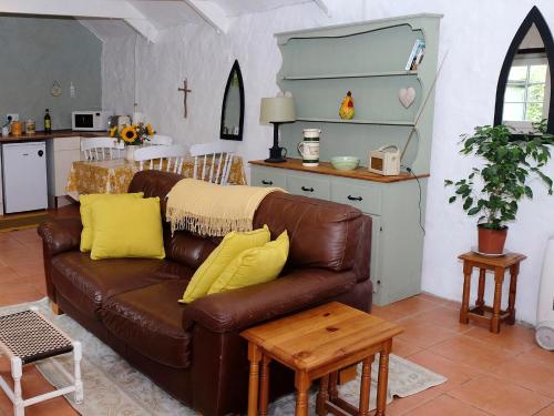 a living room with a brown leather couch with yellow pillows at Cowshed Cottage - Uk42668 in Ruan Major