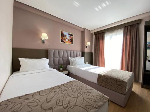 a hotel room with two beds and a window at Doanesia Premium Hotel & Spa in Tirana