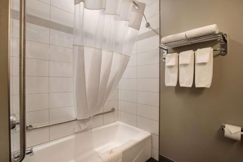 a bathroom with a tub and a shower with towels at Days Inn & Suites by Wyndham Warman in Warman