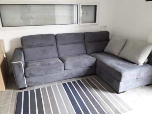 un divano grigio in soggiorno di 2 pièces avec accès piscine intérieure a Larmor-Plage