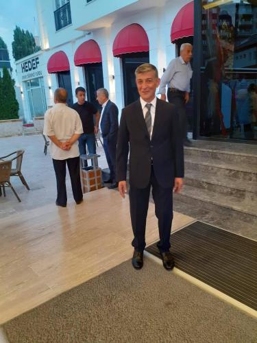 a man in a suit and tie standing in front of a building at Özkaya hotel in Sivas