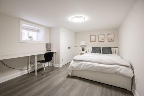 een witte slaapkamer met een bed en een bureau bij Basement Master Bedroom in Mississauga