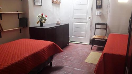 a bedroom with two beds and a door with a vase of flowers at Casa Chica in Cafayate