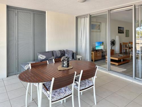 a living room with a wooden table and chairs at Blue on Blue Large One Bedroom Apartment, steps from ferry, amazing pool, wifi in Nelly Bay