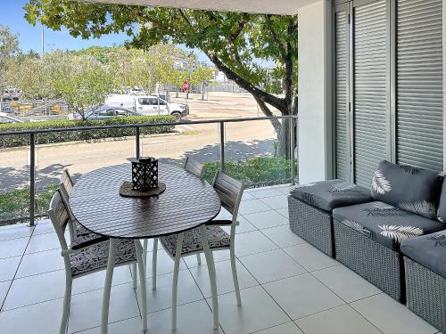 a patio with a table and chairs and a couch at Blue on Blue Large One Bedroom Apartment, steps from ferry, amazing pool, wifi in Nelly Bay