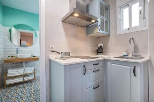 a kitchen with white cabinets and a sink and a mirror at Apartamento Al Alba in Córdoba