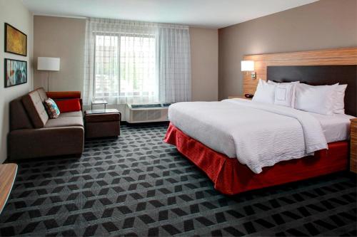 TownePlace Suites by Marriott Macon Mercer University في ماكون: غرفة فندقية بسرير كبير وكرسي
