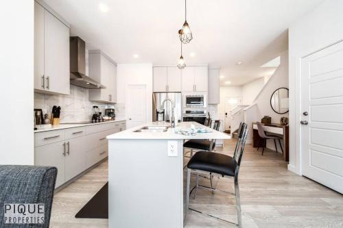 a kitchen with white cabinets and a table and chairs at *New*Chic Modern Home*King bed*Foosball*Sleeps 8! in Edmonton