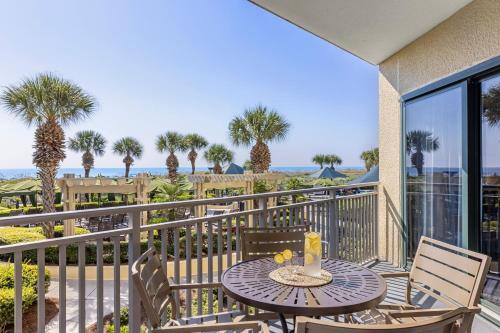 a table and chairs on a balcony with palm trees at Marriott's Barony Beach Club in Hilton Head Island