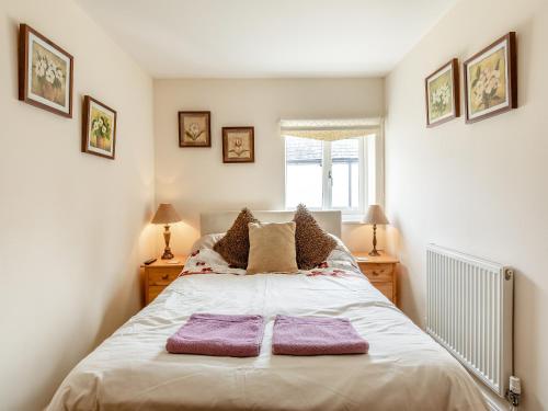 a bedroom with a bed with two purple towels on it at Birch Cottage in Watchet