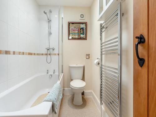 a white bathroom with a toilet and a bath tub at Birch Cottage in Watchet