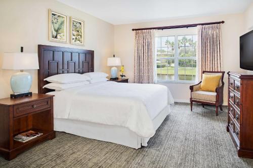a bedroom with a large white bed and a chair at Sheraton PGA Vacation Resort Port St Lucie in Port Saint Lucie