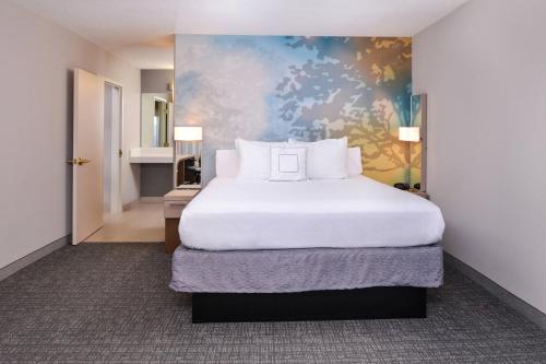a bedroom with a large white bed with a painting at Courtyard by Marriott Milwaukee North/Brown Deer in Brown Deer
