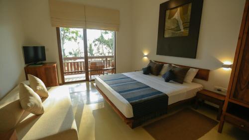 a bedroom with a bed and a large window at Pandanus Beach Resort & Spa in Bentota
