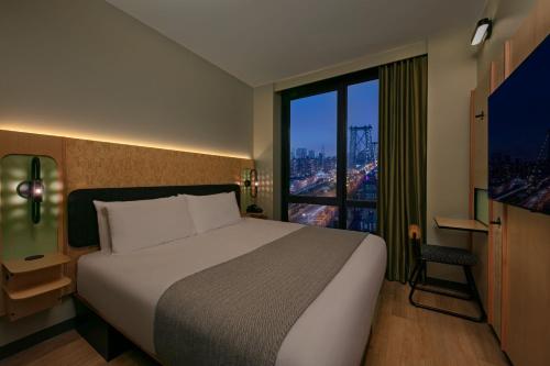 a bedroom with a large bed and a large window at Moxy Brooklyn Williamsburg in Brooklyn