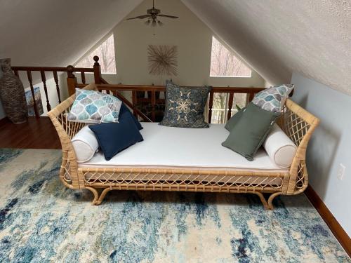 un sofá de mimbre con almohadas en una habitación en Woodland Oasis en Cumberland