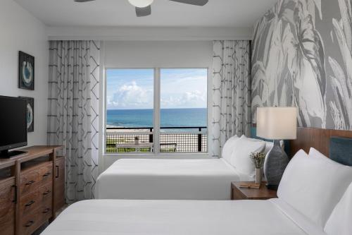 a bedroom with two beds and a window with the ocean at Marriott's Oceana Palms in Palm Beach Shores