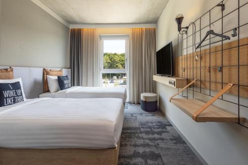 a hotel room with two beds and a television at Moxy Simmern in Simmern