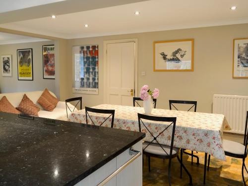 a kitchen and living room with a table and a couch at Peach Cottage in Wool