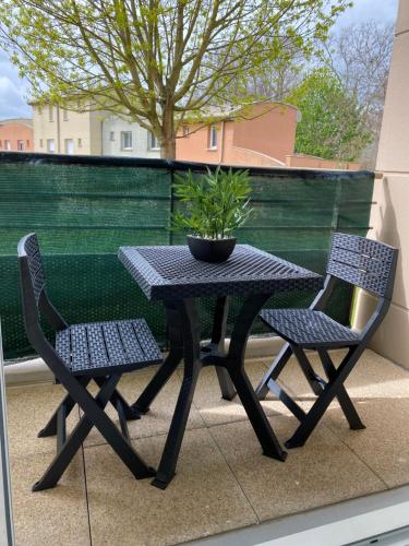 a table and two chairs with a potted plant on a balcony at Appart COSY F2 Disneyland/Val d'Europe in Montévrain