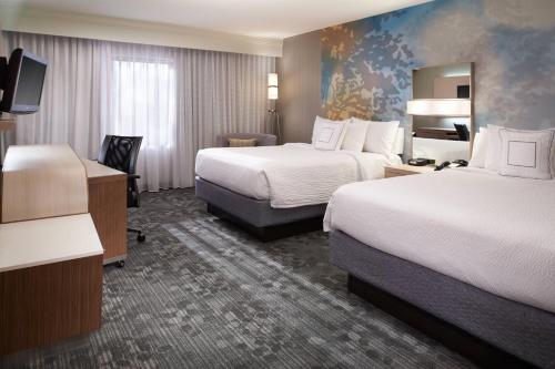 a hotel room with two beds and a television at Courtyard Toledo Maumee/Arrowhead in Maumee