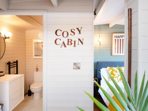 a bathroom with a toilet and a sign that reads cozy cabin at The Cosy Cabin in Clapton in Gordano