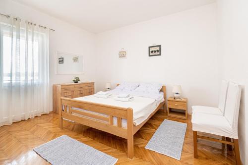 biała sypialnia z łóżkiem i krzesłem w obiekcie Apartments by the sea Pasman - 8221 w mieście Pašman