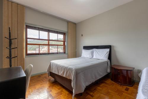 a bedroom with a bed and a table and a window at Apart Budapest - Conforto na melhor Rua de Águas de Lindóia in Águas de Lindóia