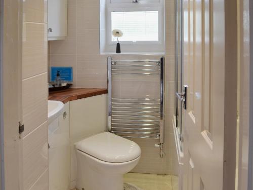 a white bathroom with a toilet and a window at 4 Eldin Hall Cottages in Cayton