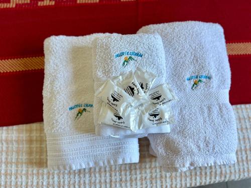 three white towels sitting on top of a bed at Palotes Sierras Cabañas in Villa Giardino