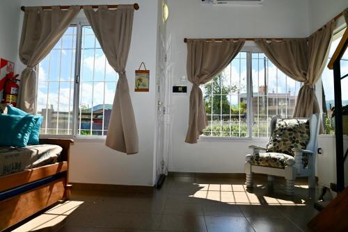 sala de estar con ventanas y silla en la parte delantera en Palotes Sierras Apart en Villa Giardino