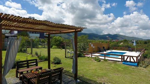 un patio trasero con piscina y pérgola de madera en Palotes Sierras Apart en Villa Giardino