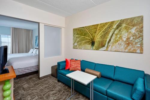 sala de estar con sofá azul y cama en Springhill Suites by Marriott Chicago Schaumburg/Woodfield Mall, en Schaumburg