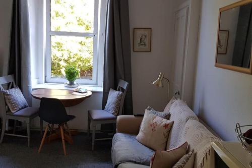 sala de estar con sofá, mesa y ventana en Nice Central Flat Walk to Princes StreetRoyal Mile, en Edimburgo