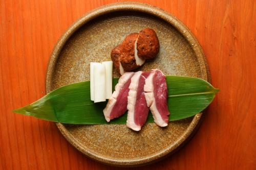 a plate with meat and cheese and a green leaf at Ryoan Fukinotou in Bungotakada