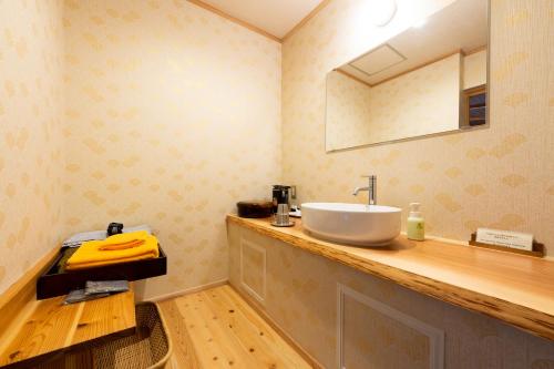 a bathroom with a sink and a mirror at Ryoan Fukinotou in Bungotakada
